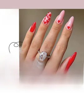 Close-up of almond-shaped press-on nails featuring hand-painted red heart designs