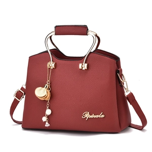 Deep red pebbled leather tote bag with elegant gold metal handles and adjustable strap