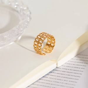 Close-up of gold hollow woven chain ring on an open book in a warm indoor setting