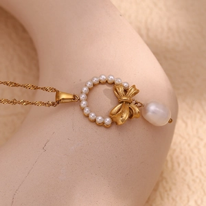 Detail of 18K gold-plated bow pendant featuring a drop pearl on a stylish necklace
