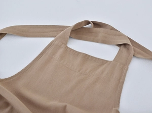 Detail of the neck strap and stitching on a beige linen garden apron with fabric texture