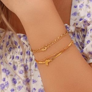 Detail of layered gold beaded and figaro chains with African map charm on wrist