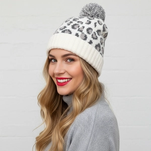 Close-up of leopard print knit beanie with fuzzy pom-pom and thick ribbed cuff detail