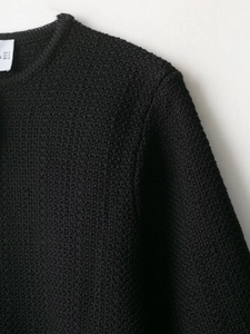 Close-up of knit fabric texture and neckline stitching with size label on black cardigan