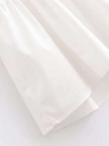 Detailed close-up of the white batwing sleeve dress hem featuring fine stitching and smooth fabric