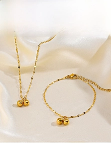 Detail of gold beaded stainless steel jewelry set on silk background with lobster clasp