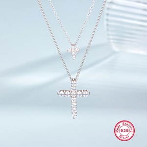 Double-layered 925 sterling silver necklace with sparkling cross pendants on blue background