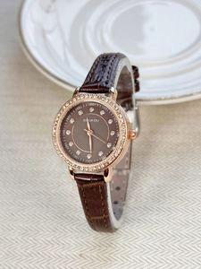 Close-up of a women's vintage watch featuring a rhinestone bezel and brown leather strap