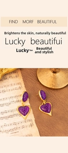 Detail of vintage heart earrings with purple textured resin and golden metal edges