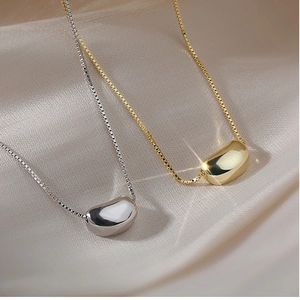 Close-up of titanium steel bean necklace pendants on silk fabric in gold and silver colors