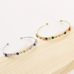 Detail of gold and silver open bangles featuring colorful marquise-cut zircon stones