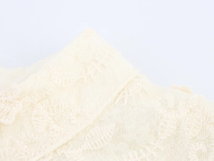 Détail de la broderie en dentelle complexe et texture en maille sur robe crème