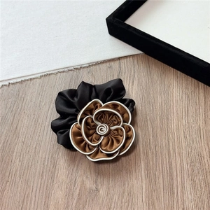 Detail of elegant satin camellia hair scrunchie with brown petals and white piping