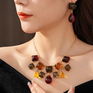 Dettaglio di orecchini e collana in resina ambrata indossati da modella in stile vintage