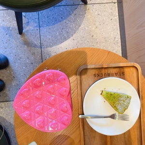 Detail of a bright pink heart-shaped bag with quilted pattern on a cafe table