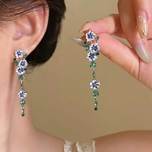 Boucles d'oreilles dorées avec fleurs en émail bleu et blanc et longs glands sur mannequin
