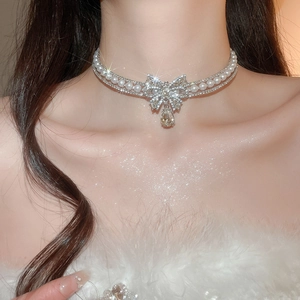 Detail of double-layer pearl choker with a sparkling crystal bow and teardrop pendant