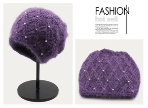 Dettaglio del cappello in maglia viola con trama a rombi e perle bianche applicate