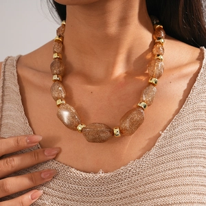 Macro detail of acrylic irregular champagne gold beads on a retro style necklace