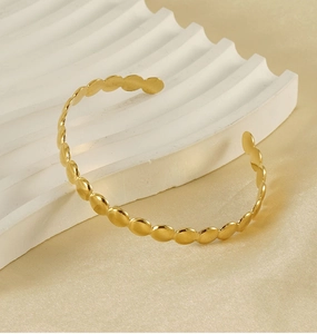 Detailed macro view of gold-plated circular links on an adjustable stainless steel bangle