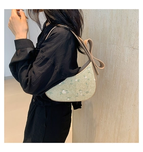 Detail of green crescent bag featuring white floral embroidery and large khaki shoulder bow
