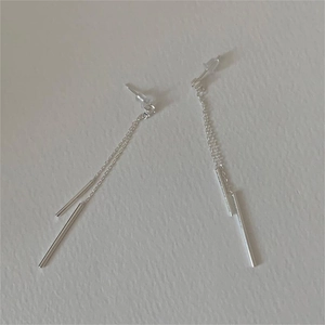 Macro detail of silver tassel chain drop earrings showing the fine linear metal texture