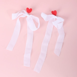 Cute red heart earrings with white lace ribbon tassels on a pink background