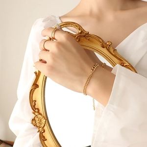 Double-layered gold beaded bracelet with minimalist matching rings on woman's hand