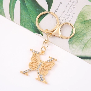 Detail of crystal butterfly and letter K keychain with gold lobster clasp on a leaf