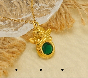 Détail d'un pendentif ange plaqué or 18k avec une pierre verte et une finition polie
