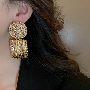 Macro detail of vintage gold coin earrings with textured rectangular drop on a model