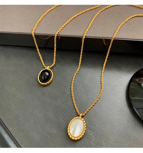 Close-up of gold-plated necklaces with black onyx and white shell oval pendants