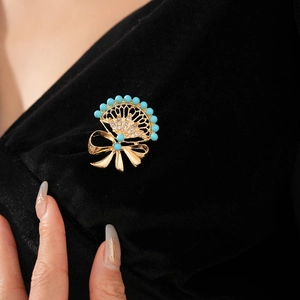 Close-up of vintage gold brooch with fan design, blue beads and diamonds on black velvet