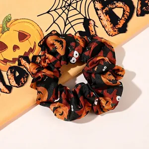 Detailed view of Halloween scrunchies with pumpkin and bat patterns on satin fabric