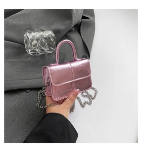 Pink glossy crocodile pattern mini bag held by hand to show size and chain strap detail