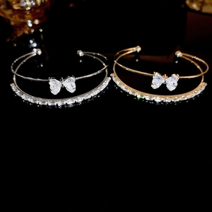 Detail of silver and gold double-layered bracelets with zircon bow and square stones