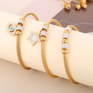 Detailed view of gold snake chain bracelets with evil eye and star charms on display
