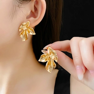 Boucles d'oreilles feuilles dorées texturées portées par un mannequin chic