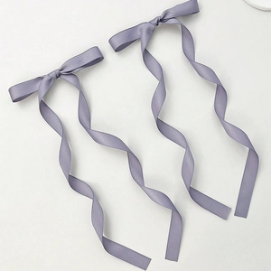 Detailed close-up of a pair of lavender ribbon bow hair clips with long spiral tails