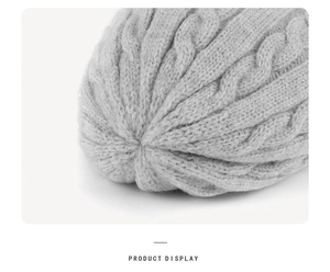 Detailed close-up of grey knit beanie with cable pattern texture and top stitching detail