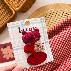 Detail of three red fabric hair clips on a bunny card including a cute bear and bow