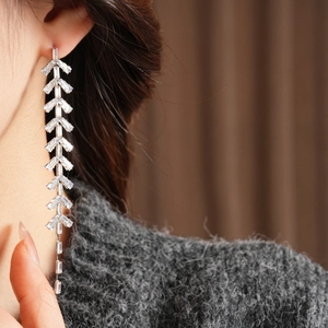 Macro shot of silver tassel earrings with baguette cut zircon stones in leaf design