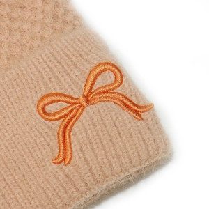 Macro detail of orange bow embroidery on soft khaki knit fabric and warm fluffy texture