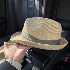 Detail of woven straw sun hat with an olive green ribbon trim and fine texture