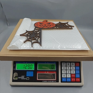 Functional shot showing a Halloween wooden pumpkin corner decor being weighed at 129.0g