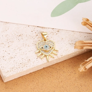 Detail of gold evil eye heart pendant with blue zircon stones on a rustic stone background