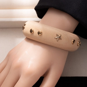 Close-up of wide wood bangle with gold star studs and natural grain texture
