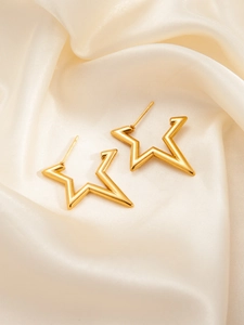 Detailed view of gold star-shaped earrings on cream silk fabric texture backdrop