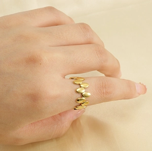 Détail d'une bague dorée irrégulière à pois sur tissu en soie portée par un mannequin