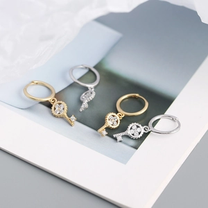 Detail view of gold and silver S925 four-leaf clover key hoop earrings with shiny zircons